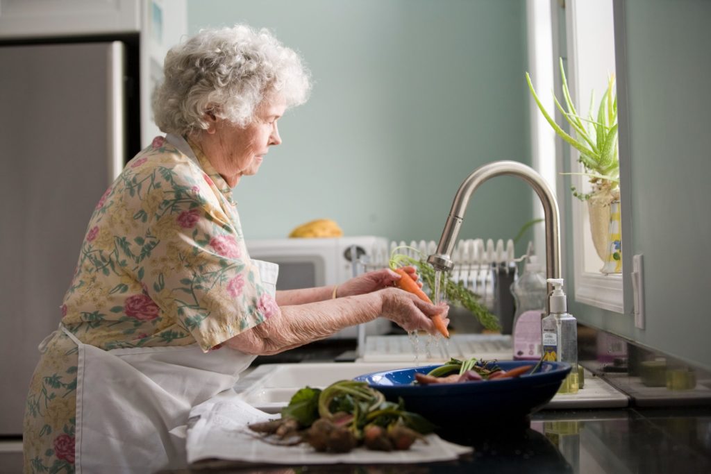 Senior Citizen washing Vegetables in the sink