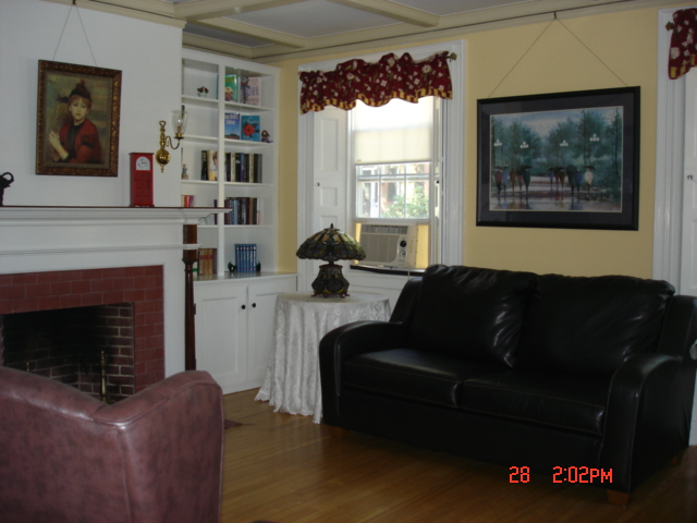 The interior of a home with a dark black leather couch, fireplace, and various other furniture. The walls are yellow.