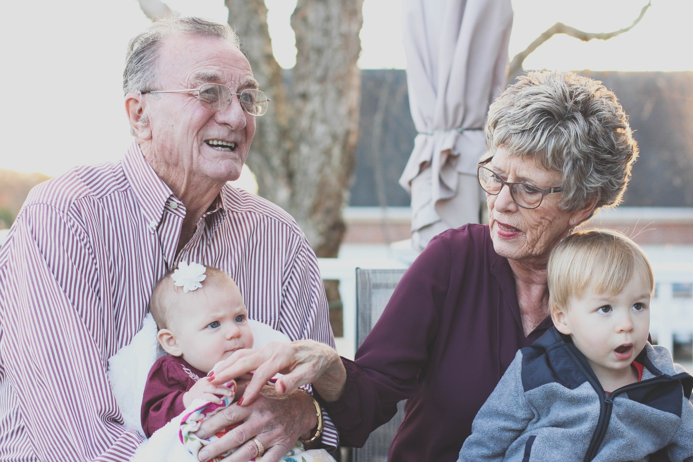 An older couple holding two young children in their arms.