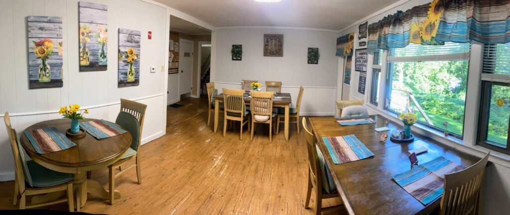 A dining room showing three different tables; there are pictures on the walls and a hardwood floor